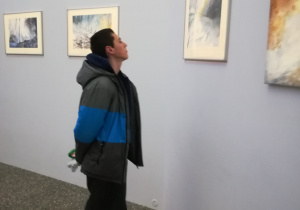 Uczeń ogląda wystawę akwareli Tomasza Olszewskiego w CKiS Wieża Ciśnień